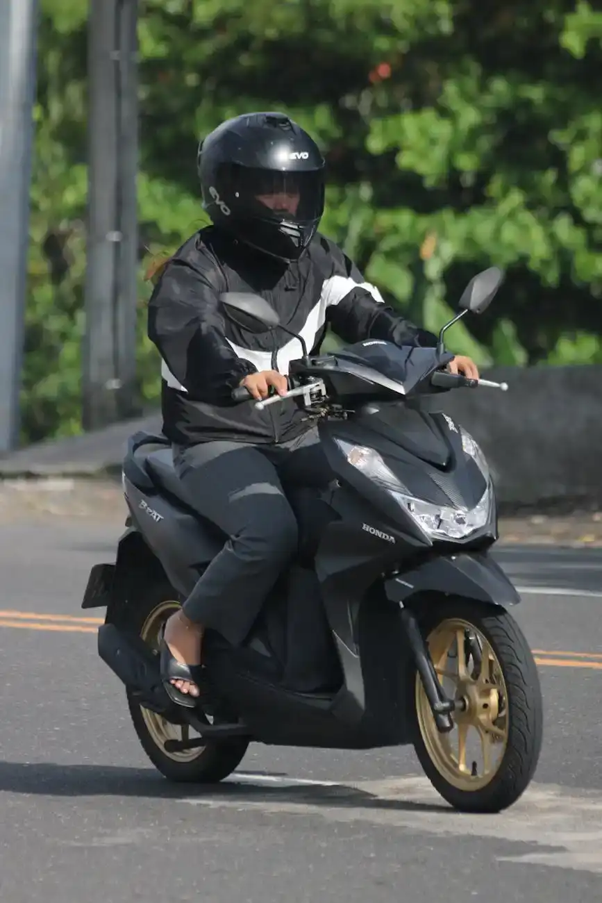 person riding scooter on sunny road